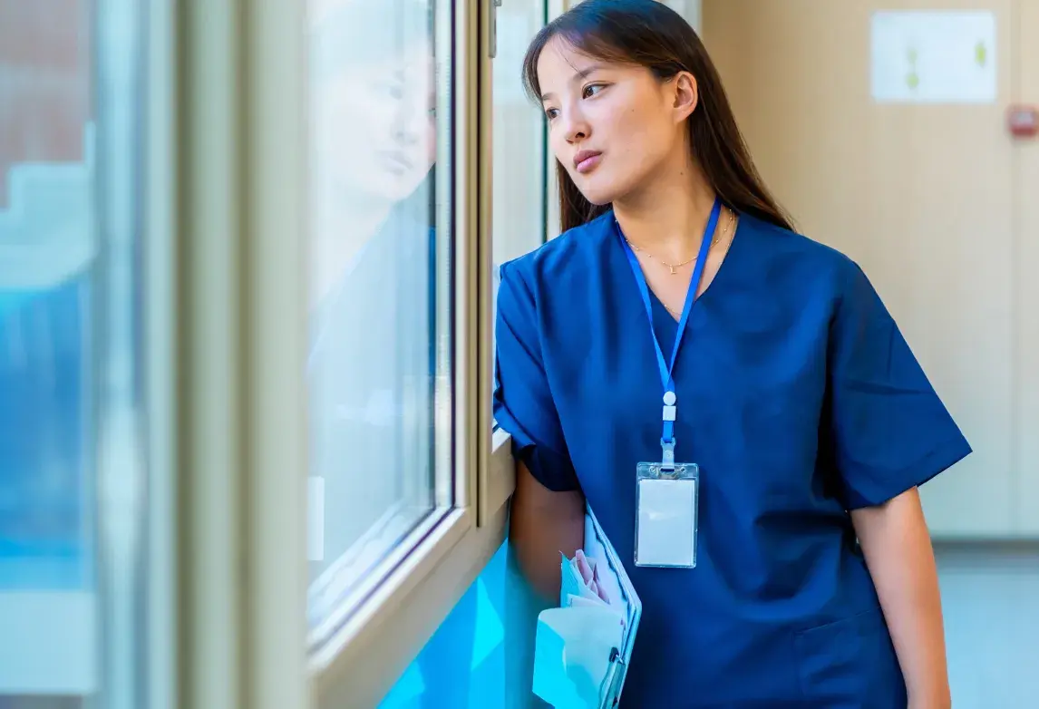 a healthcare student looking out the window and thinking about her emotional health