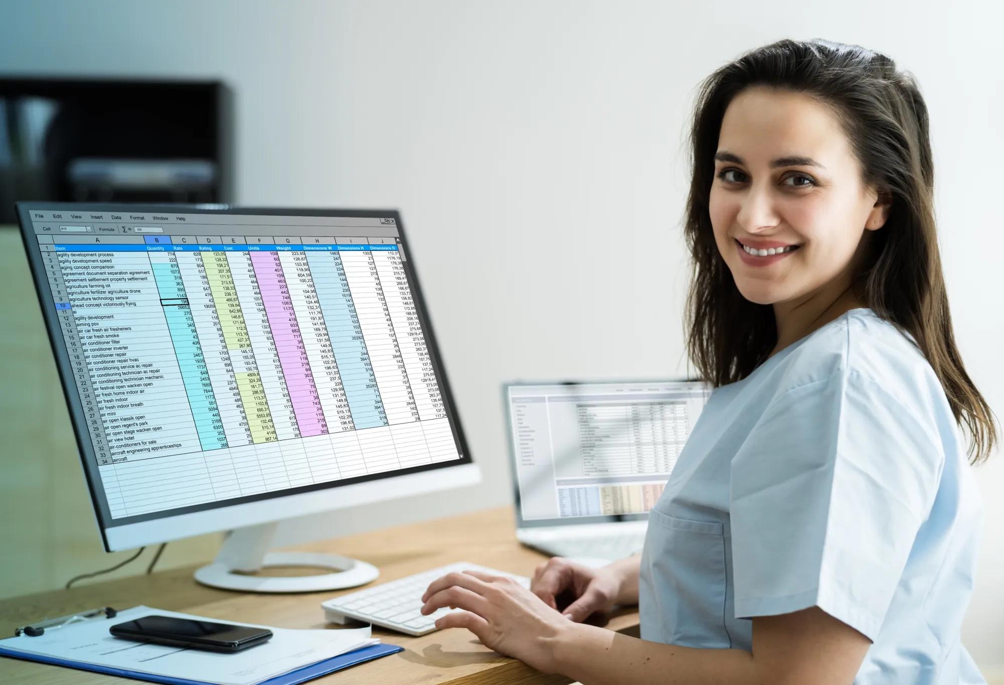 A medical biller and coder sits in front of her spreadsheets at her desk.