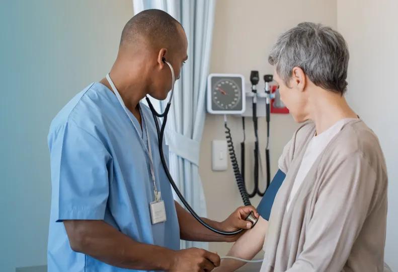 a medical assistant taking a patient’s blood pressure in a healthcare office after completing a medical assistant program