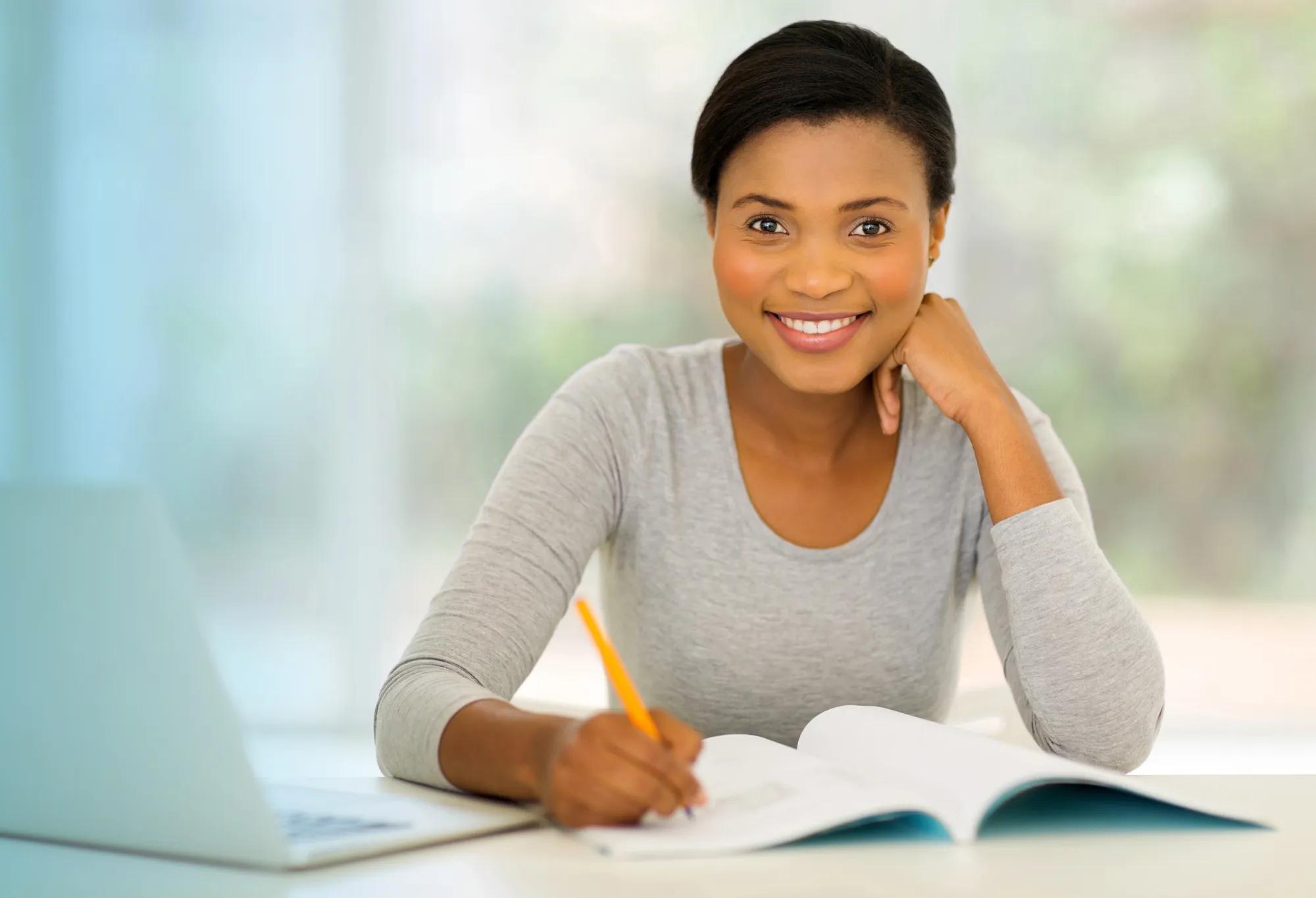 An adult learner taking notes from a textbook while going back to school