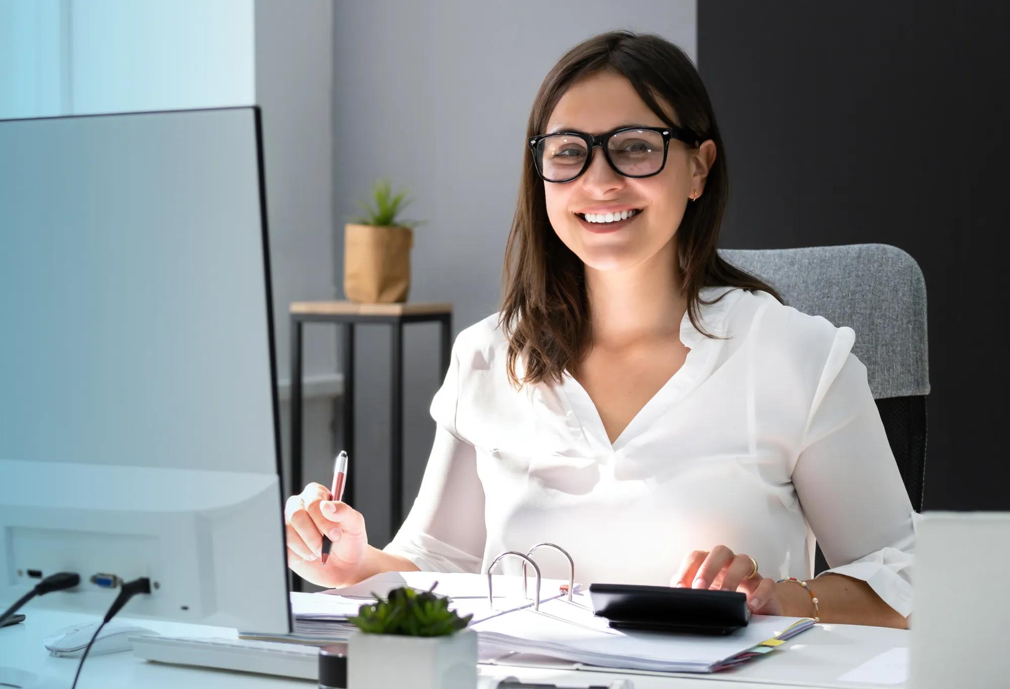 A person with a degree in healthcare accounting sitting at a desk and working on a computer while using a calculator