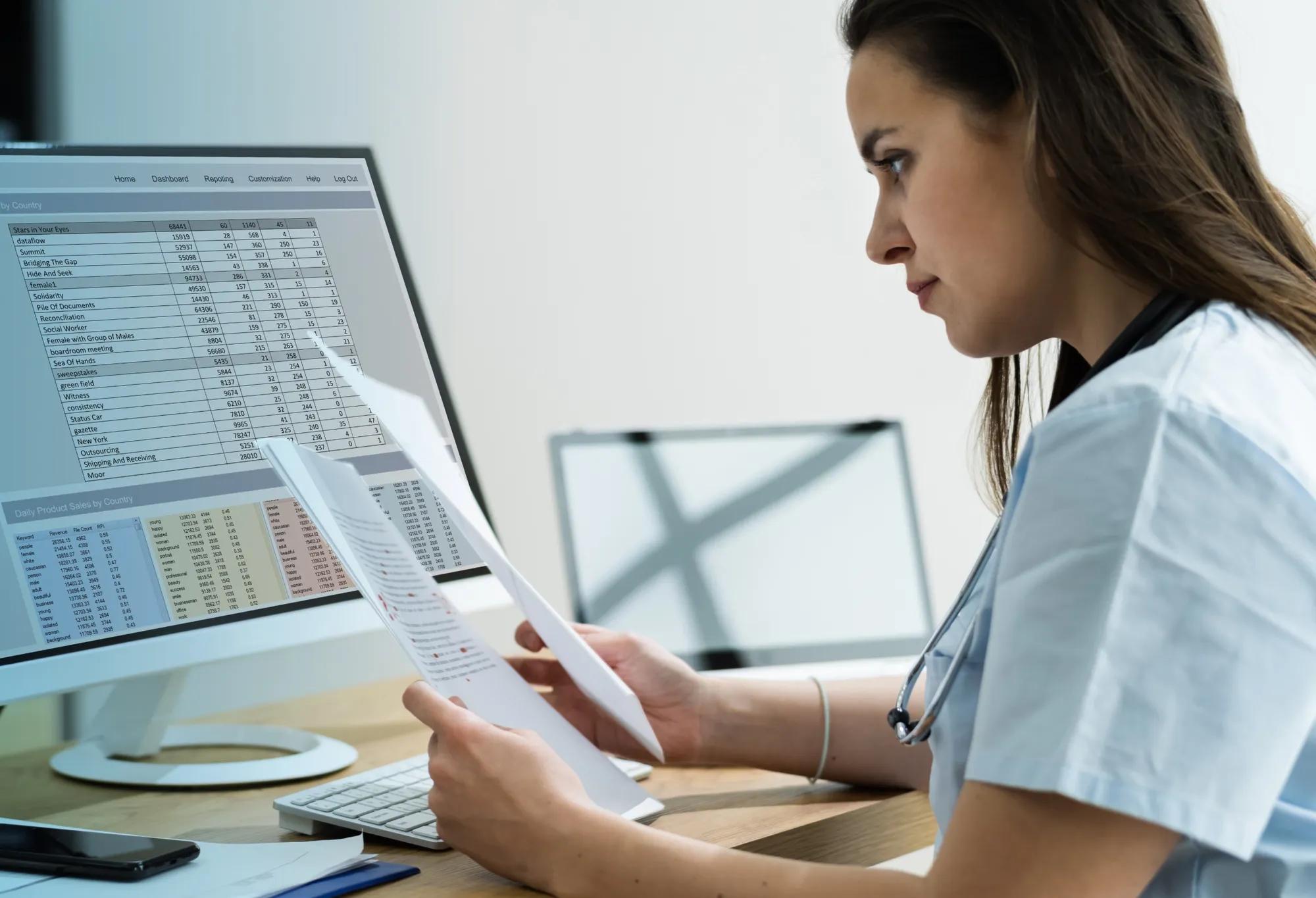 A medical coder working on a computer at a desk in a healthcare office